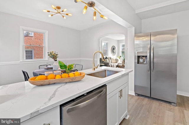 kitchen featuring white cabinets, appliances with stainless steel finishes, light stone countertops, light hardwood / wood-style flooring, and sink