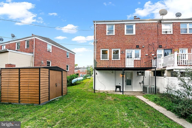 rear view of property featuring a yard, a storage unit, and central AC unit