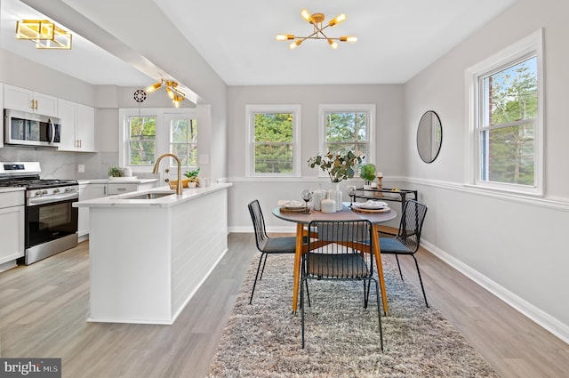 dining space with an inviting chandelier, light hardwood / wood-style flooring, and sink