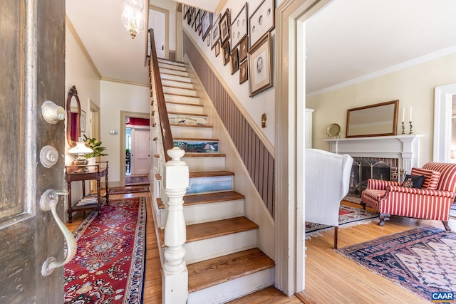 staircase with ornamental molding, a fireplace, and hardwood / wood-style flooring