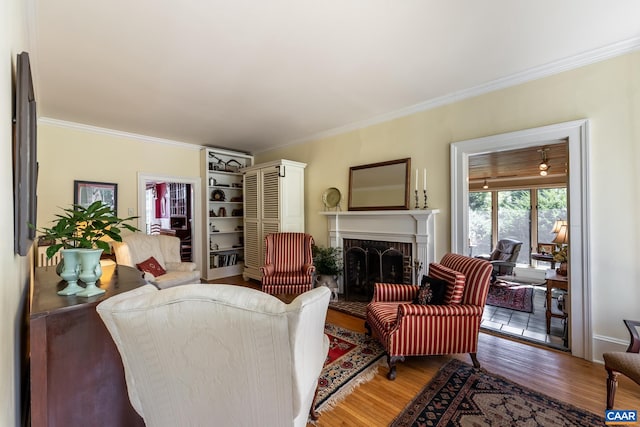 living room with crown molding, wood-type flooring, and a brick fireplace