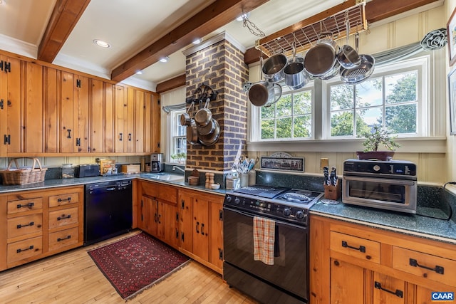 kitchen featuring beam ceiling, sink, black appliances, decorative columns, and light hardwood / wood-style floors