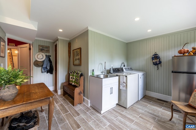 laundry room featuring sink, crown molding, cabinets, washing machine and clothes dryer, and light hardwood / wood-style floors