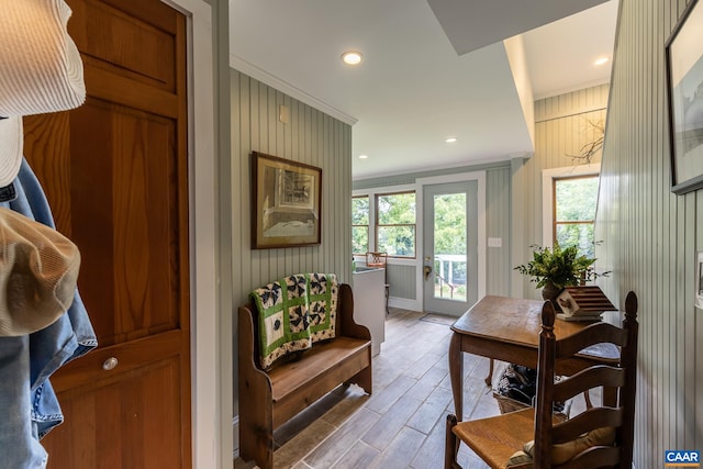 doorway featuring crown molding, wood walls, and light wood-type flooring