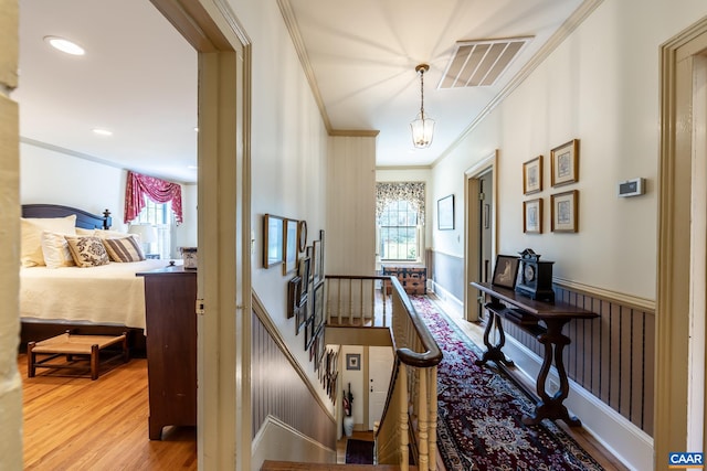 corridor with light hardwood / wood-style flooring and ornamental molding