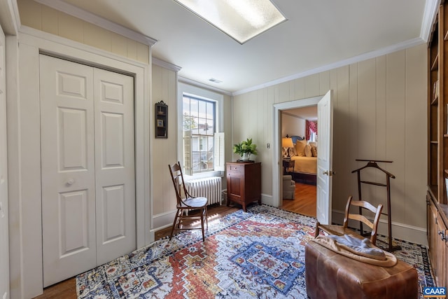 living area featuring light hardwood / wood-style floors, crown molding, and radiator heating unit