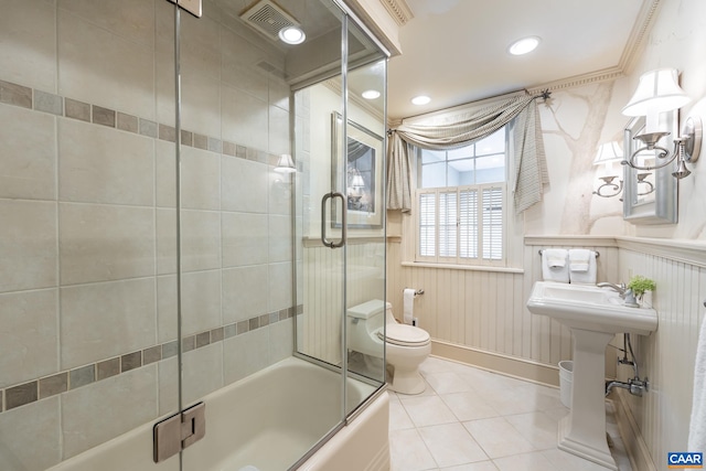 bathroom featuring bath / shower combo with glass door, toilet, and tile patterned flooring