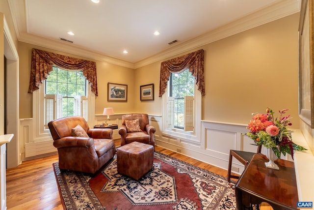 living room with ornamental molding, a healthy amount of sunlight, and light wood-type flooring