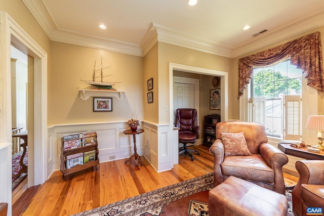 living area with wood-type flooring and ornamental molding