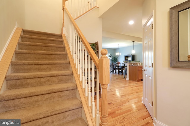 stairs featuring a chandelier and hardwood / wood-style flooring