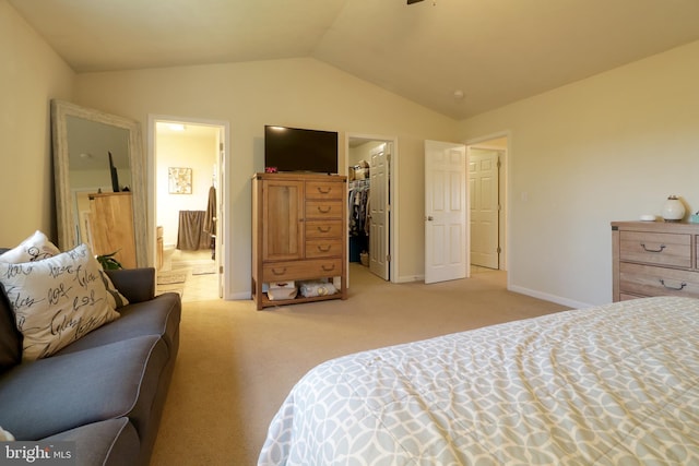 bedroom featuring a closet, vaulted ceiling, light colored carpet, and a walk in closet