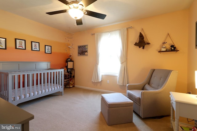 carpeted bedroom featuring a crib and ceiling fan