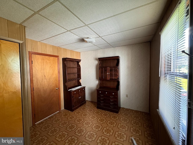 interior space featuring wood walls and a drop ceiling