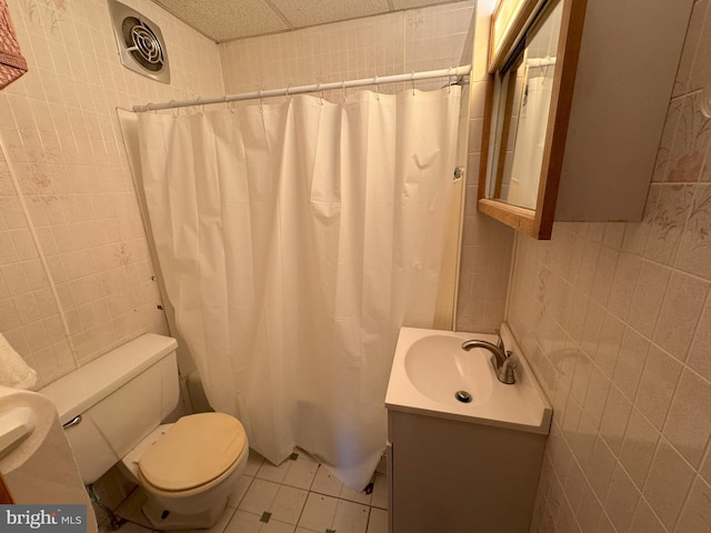 bathroom featuring vanity, toilet, tile patterned floors, and tile walls