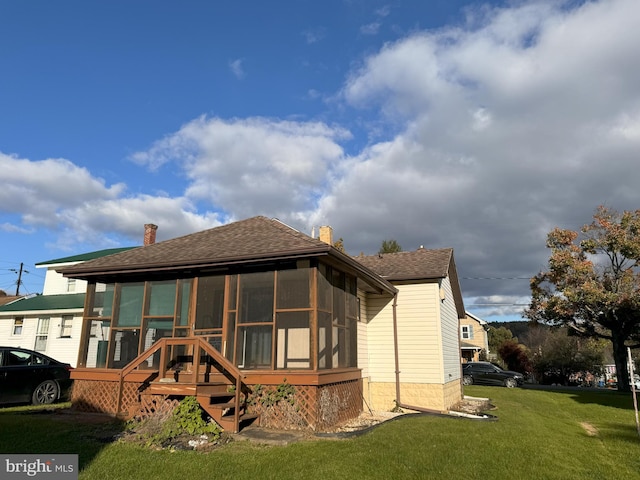 back of house featuring a lawn and a sunroom