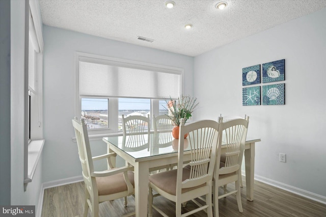 dining space featuring a textured ceiling and wood-type flooring