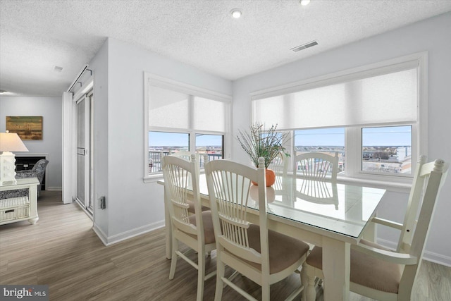 dining area with a textured ceiling and hardwood / wood-style flooring