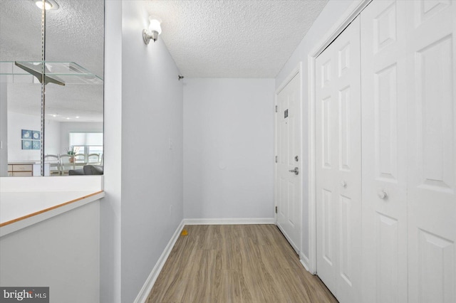 corridor featuring light hardwood / wood-style floors and a textured ceiling