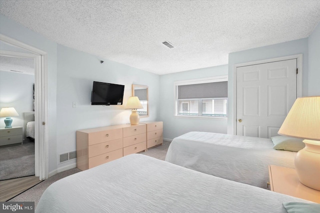 bedroom with a textured ceiling and light colored carpet