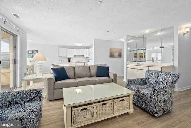 living room with light hardwood / wood-style floors, a textured ceiling, and sink