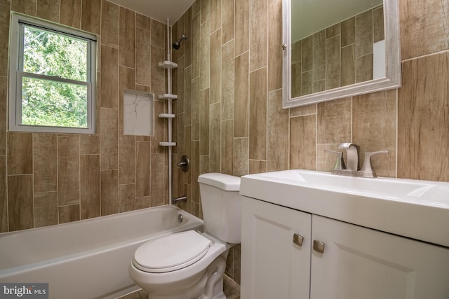 full bathroom with tile walls, vanity, tiled shower / bath combo, and toilet