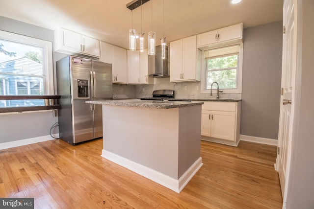 kitchen with wall chimney exhaust hood, appliances with stainless steel finishes, a center island, and white cabinets