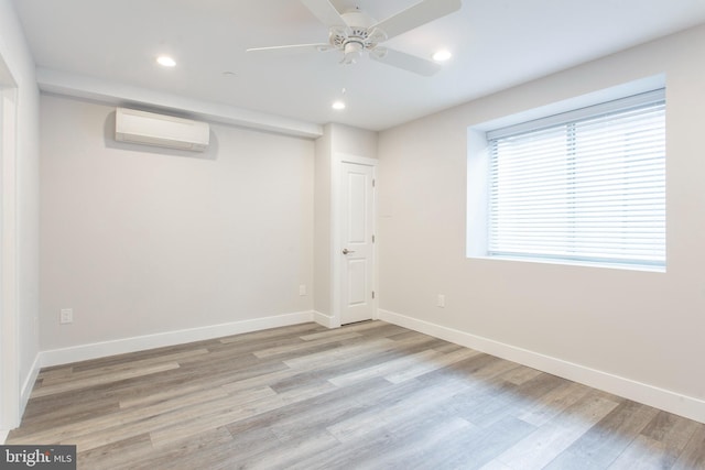 empty room with light hardwood / wood-style flooring, a wall mounted air conditioner, and ceiling fan