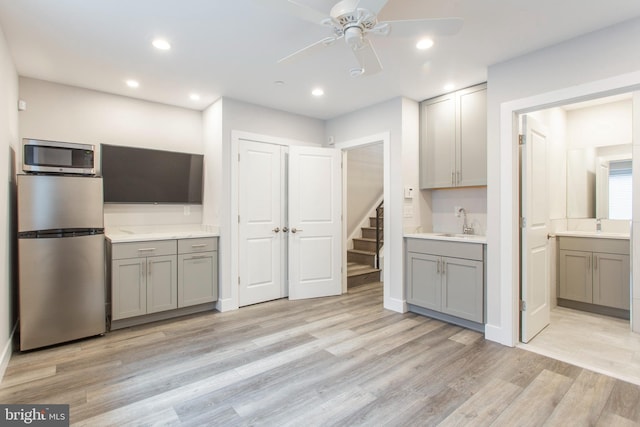 kitchen with light hardwood / wood-style floors, stainless steel appliances, and gray cabinetry