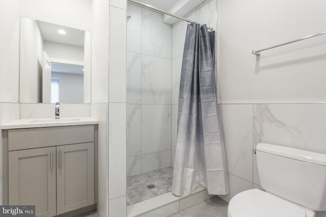 bathroom with tile walls, vanity, a shower with shower curtain, and toilet