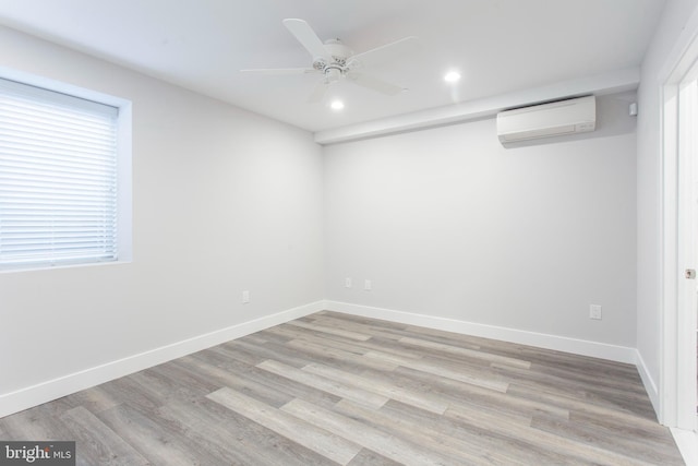 empty room featuring light hardwood / wood-style floors, a wall mounted AC, and plenty of natural light