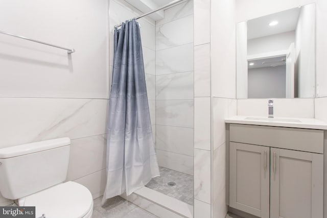 bathroom with tile walls, vanity, toilet, and walk in shower