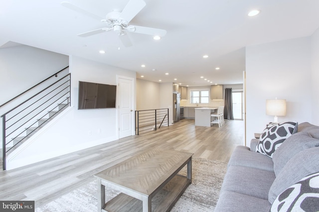 living room featuring sink, light wood-type flooring, and ceiling fan