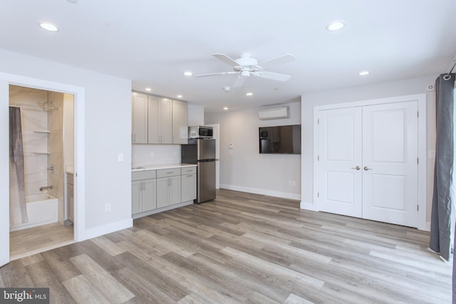 kitchen with gray cabinetry, light hardwood / wood-style floors, ceiling fan, and stainless steel fridge