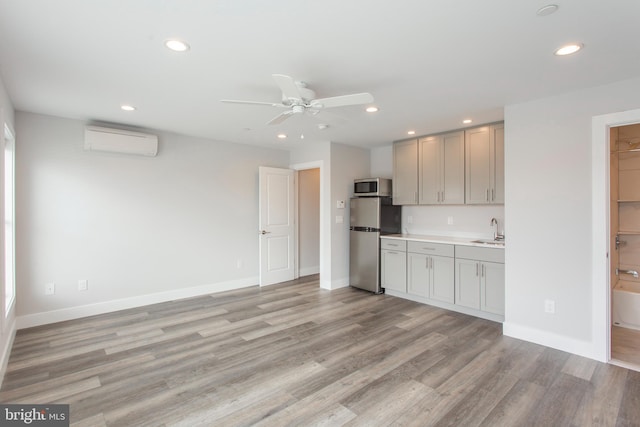 kitchen featuring sink, a wall mounted air conditioner, light hardwood / wood-style floors, and stainless steel appliances