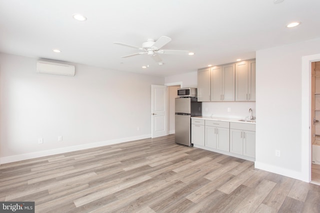 kitchen featuring ceiling fan, light hardwood / wood-style flooring, an AC wall unit, stainless steel appliances, and sink