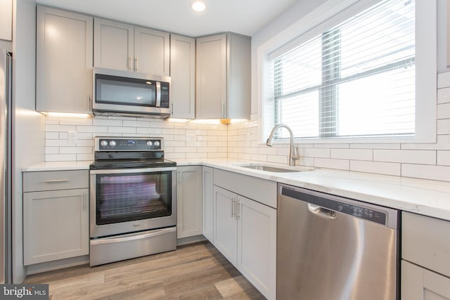 kitchen with gray cabinets, sink, stainless steel appliances, and light wood-type flooring