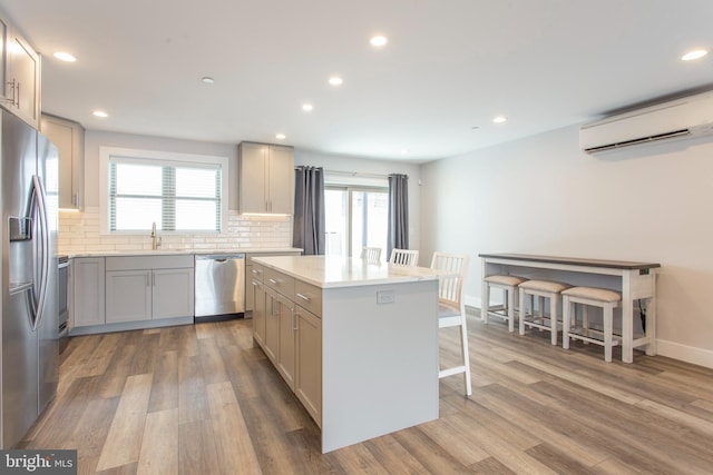 kitchen featuring appliances with stainless steel finishes, a wall unit AC, a center island, and wood-type flooring