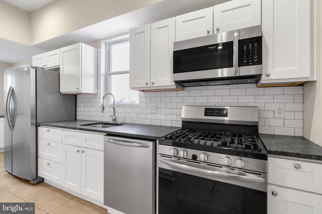 kitchen featuring white cabinets, backsplash, light tile patterned floors, sink, and stainless steel appliances