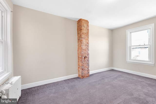 carpeted empty room featuring radiator heating unit