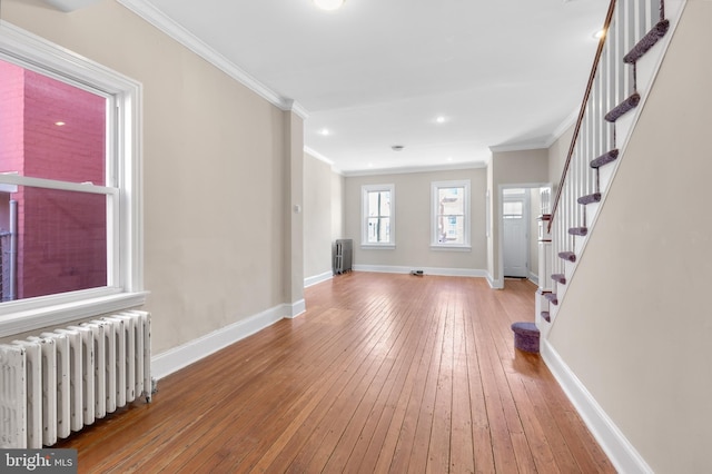 interior space featuring wood-type flooring, radiator heating unit, and ornamental molding