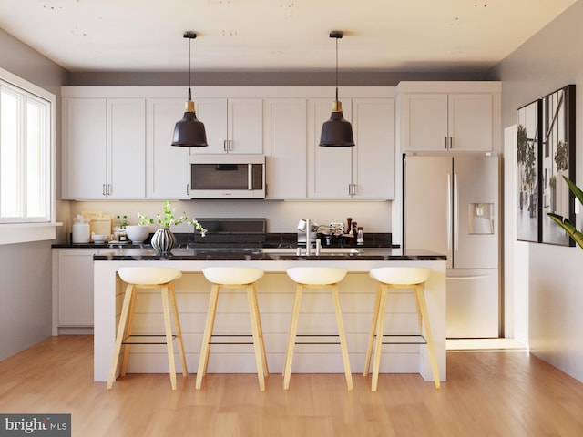 kitchen with a center island with sink, white cabinetry, decorative light fixtures, and white fridge with ice dispenser