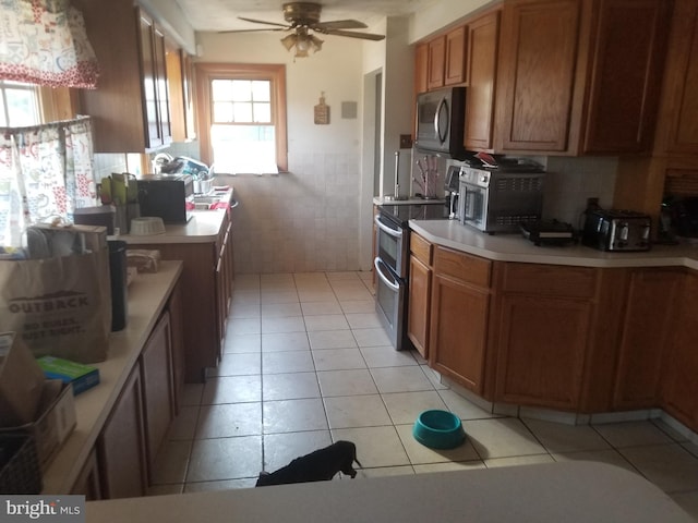 kitchen with light tile patterned floors, ceiling fan, and stainless steel electric range oven