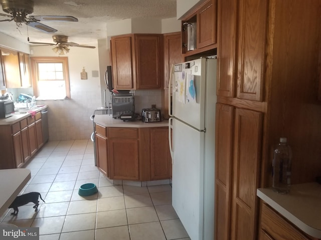 kitchen featuring a textured ceiling, light tile patterned floors, ceiling fan, and white fridge