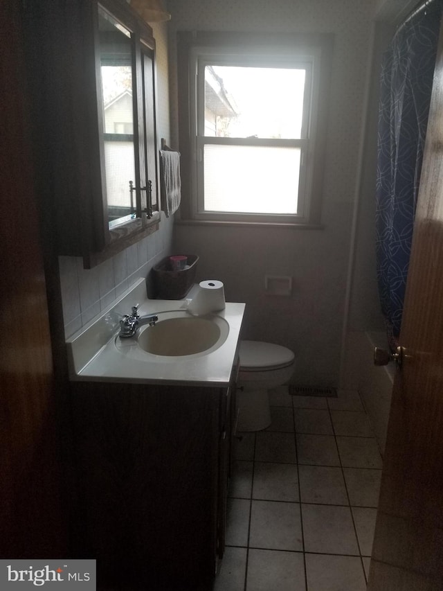 full bathroom featuring a wealth of natural light, vanity, tile patterned floors, and toilet