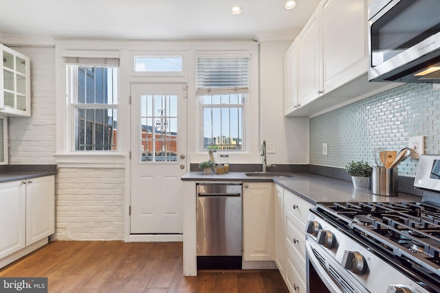 kitchen with wood-type flooring, backsplash, sink, white cabinetry, and appliances with stainless steel finishes