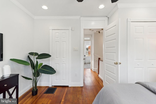 bedroom with dark wood-type flooring, crown molding, and ceiling fan