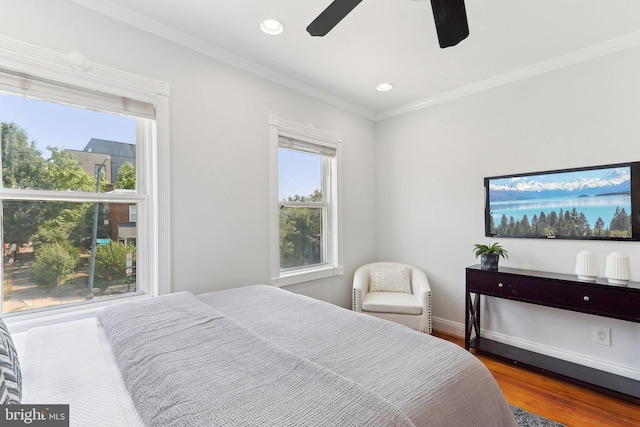 bedroom featuring ceiling fan, ornamental molding, multiple windows, and hardwood / wood-style floors