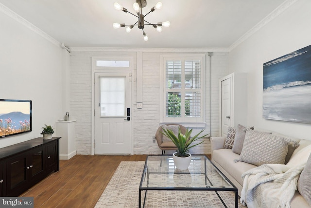 living room featuring ornamental molding, brick wall, an inviting chandelier, and dark hardwood / wood-style flooring