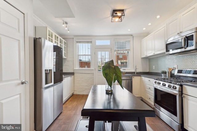 kitchen featuring sink, hardwood / wood-style floors, white cabinetry, appliances with stainless steel finishes, and tasteful backsplash