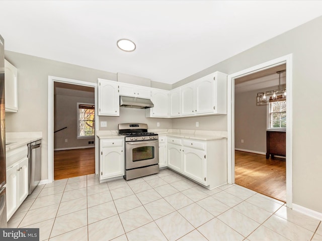 kitchen featuring hanging light fixtures, light wood-type flooring, white cabinetry, stainless steel appliances, and a chandelier